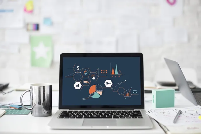 Portátil con gráficas de ingresos en la pantalla sobre una mesa de oficina