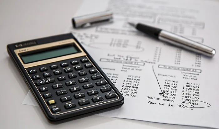 Calculadora y bolígrafo sobre una hoja con importes y fechas
